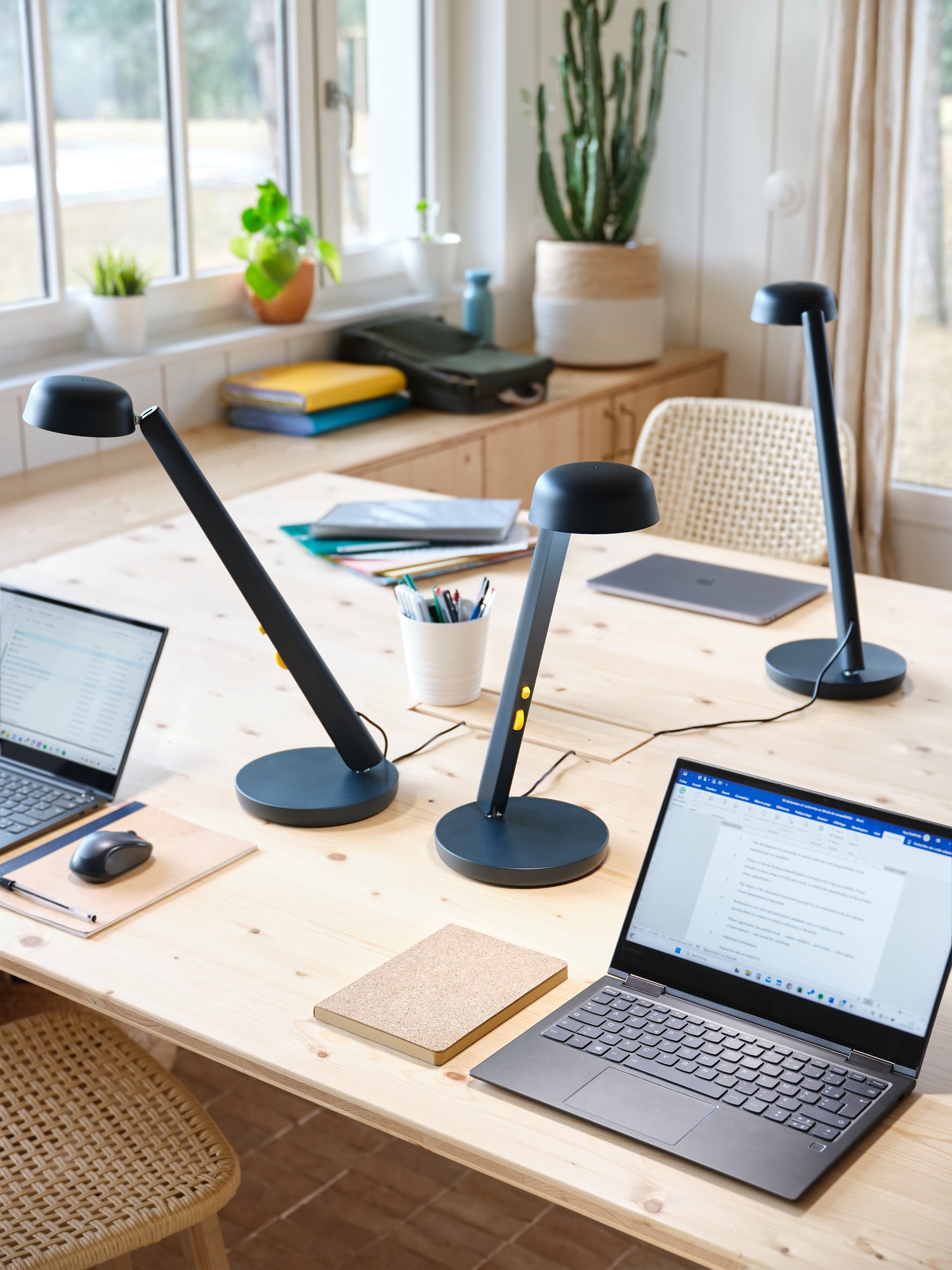 3 lampes de couleur bleu nuit posées sur des bureaux en bois avec des ordinateur dans un espace de co-working